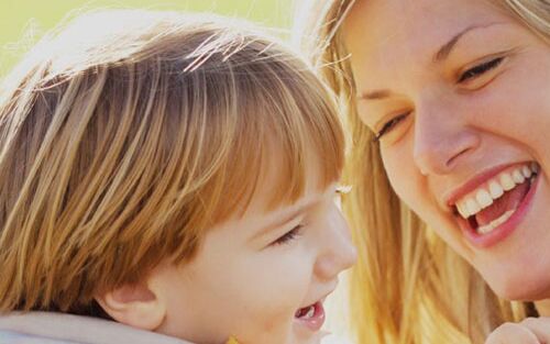 Eine Mutter und ihr Kind lachen glücklich zusammen in der Sonne und genießen die gemeinsame Zeit als Familie.